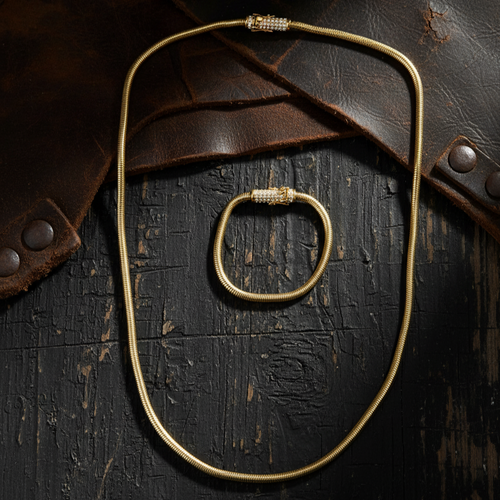 Gold necklace on a textured dark surface with leather accents