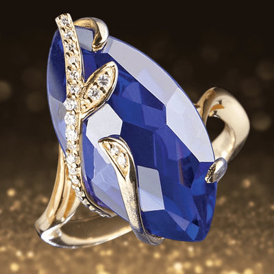 Tanzania Vine Ring featuring a large marquise-cut blue gemstone set in sterling silver with gold plating, accented with delicate vine-inspired details and small sparkling crystals.