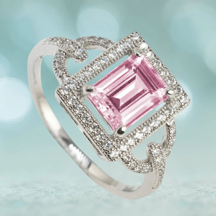 Astoria Pink Ring featuring a sterling silver band plated with rhodium, showcasing a square pink gemstone surrounded by sparkling accents, designed for women’s jewelry.