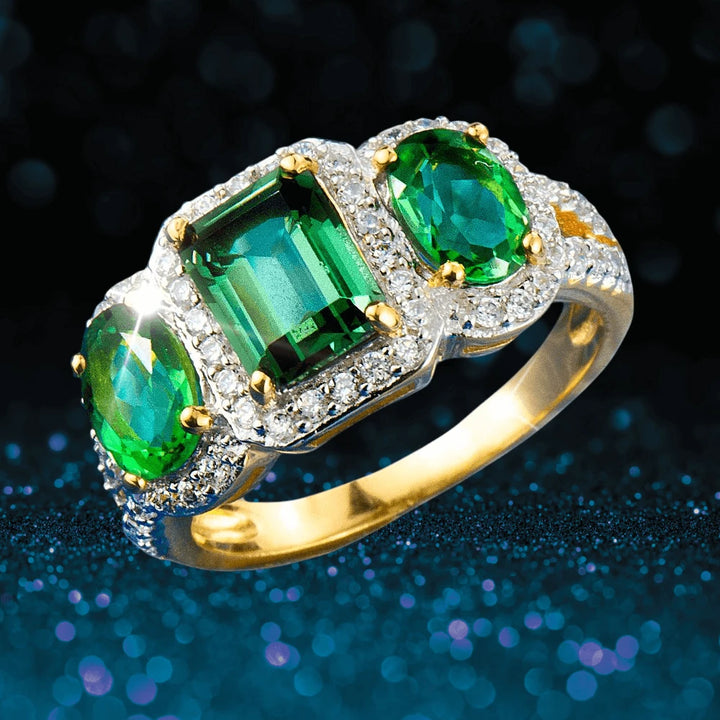 Fortuna Ring featuring sterling silver with gold plating, adorned with three vibrant green gemstones and surrounded by sparkling accents, designed for women’s jewelry collections.
