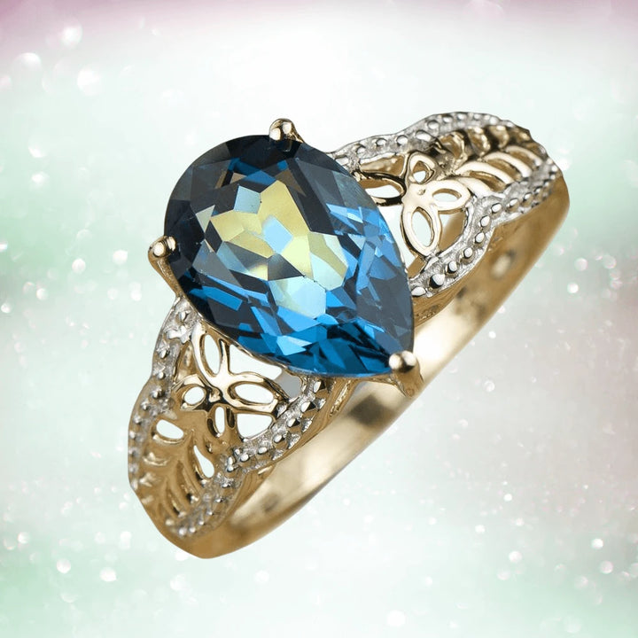 Parade Topaz Ring featuring a pear-shaped blue topaz set in sterling silver with gold plating, designed for women with intricate filigree detailing.
