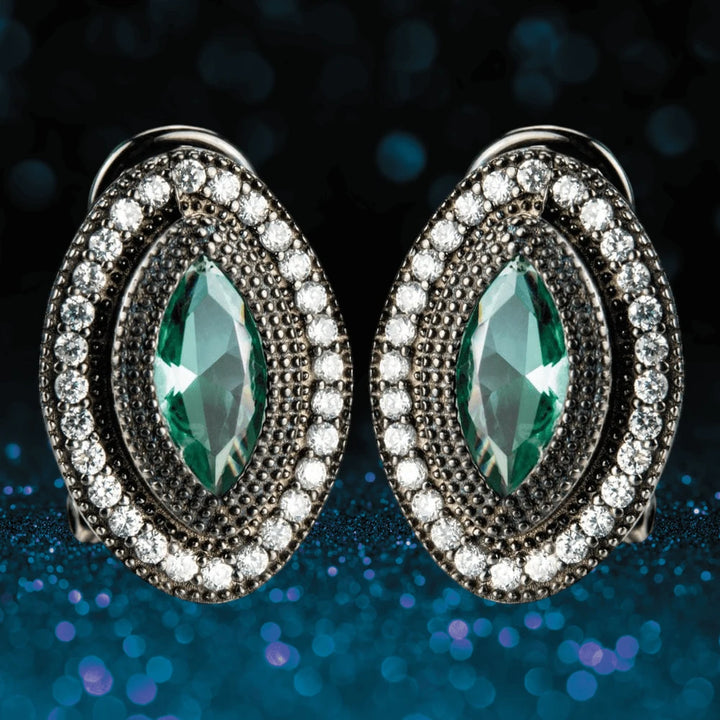 Black Orchid Earrings featuring sterling silver with a central marquise green gemstone surrounded by a halo of sparkling clear stones, designed for women’s elegant jewelry collections.
