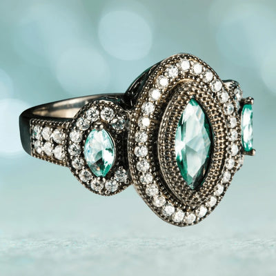 Black Orchid Ring in sterling silver featuring a central marquise-cut aqua gemstone surrounded by two rows of small clear stones, designed for female jewelry lovers.