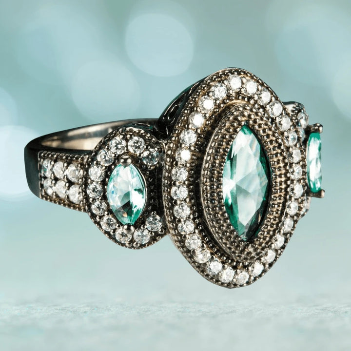 Black Orchid Ring in sterling silver featuring a central marquise-cut aqua gemstone surrounded by two rows of small clear stones, designed for female jewelry lovers.