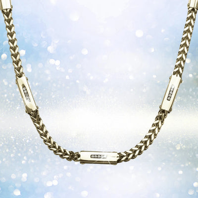 Quadrant Steel Necklace in gold-plated stainless steel for men, featuring a sleek chain design with three embedded sparkling accents against a shimmering background.