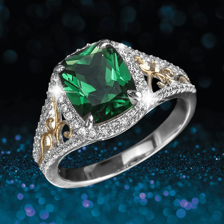 Aurora Ring featuring a two-tone sterling silver band with intricate gold details and a large radiant green gemstone centerpiece surrounded by small clear stones.