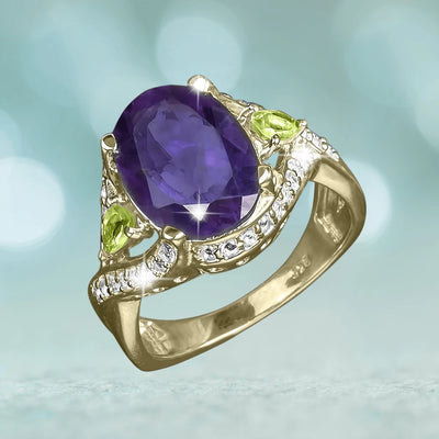 Sansiri Amethyst Ring features a large oval amethyst gemstone set in sterling silver with gold plating, accented by green peridot stones and small clear crystals for an elegant female jewelry piece.
