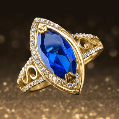 Ceylon Marquise Ring featuring a large marquise-cut deep blue gemstone set in sterling silver with gold plating and accented by sparkling clear crystals around the band for women’s jewelry.