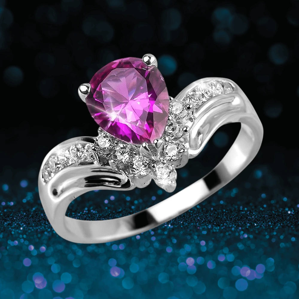 Rosa Primera Ring featuring a pear-shaped pink gemstone set in rhodium-plated sterling silver with accenting clear stones, designed for women’s jewelry collections.