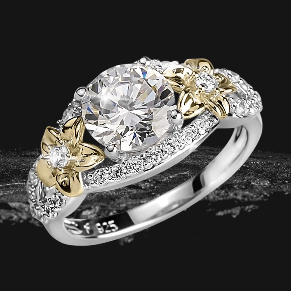 Floria Ring featuring a two-tone sterling silver band with intricate floral accents and a large central sparkling gemstone, designed for women’s jewelry collections.