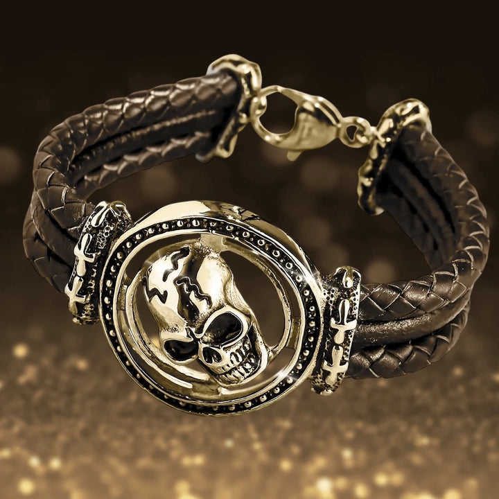 Skull Arena Gold Bracelet featuring a bold gold-plated stainless steel skull centerpiece on a woven black leather band, designed for a striking male jewelry statement.