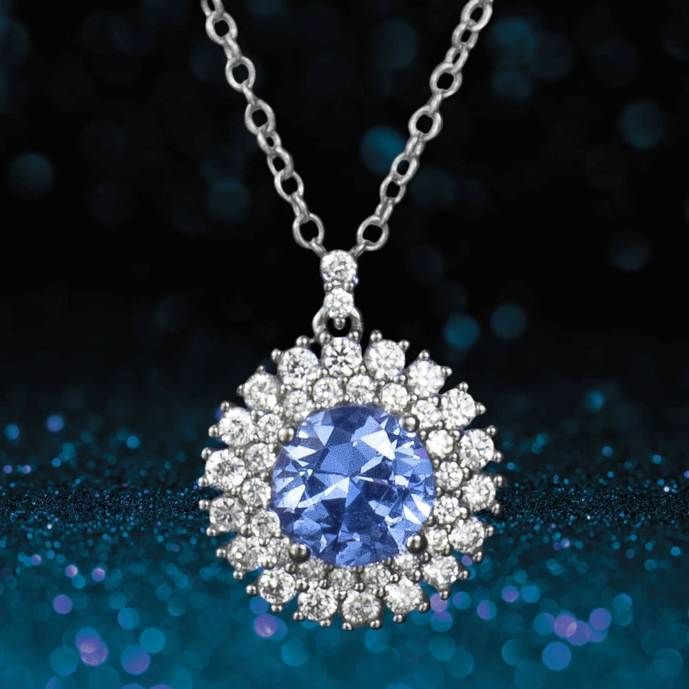 Idols Eye Pendant featuring a round blue gemstone surrounded by sparkling clear stones, set in sterling silver with rhodium plating, designed for women’s jewelry.