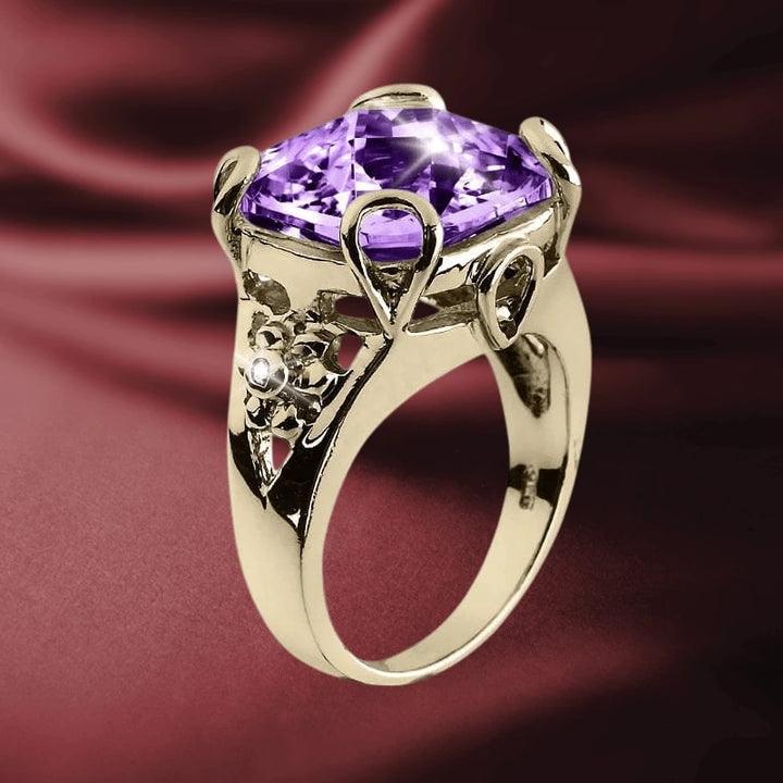Golden Fascination Ring featuring a large purple gemstone set in gold-plated sterling silver with intricate floral detailing, designed for women’s jewelry collections.