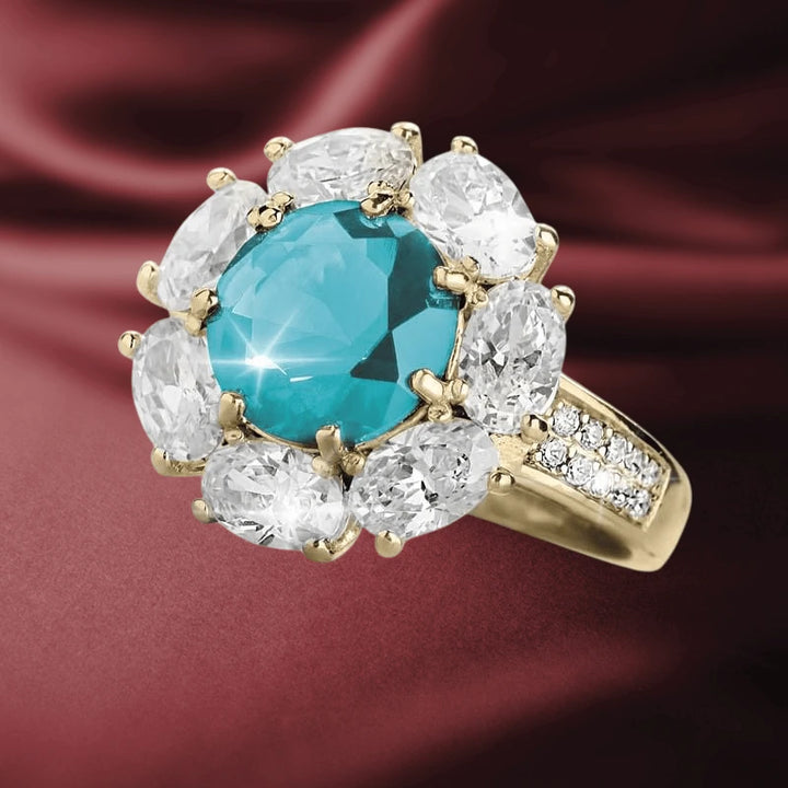 Glacial Cluster Ring featuring a gold-plated sterling silver band with a central blue gemstone surrounded by sparkling clear stones, designed for women’s jewelry collections.