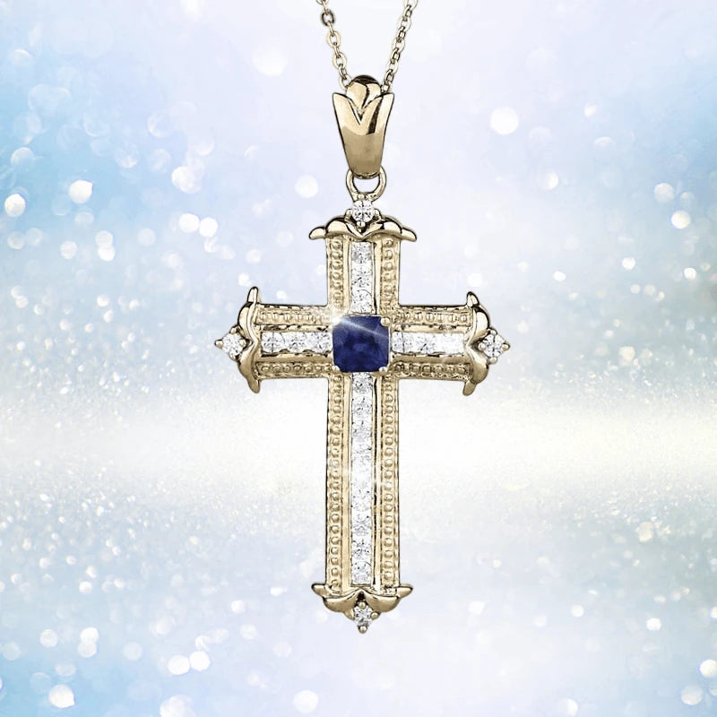 Sapphira Cross Pendant featuring a sterling silver cross plated in gold with a central blue sapphire gemstone, designed as a women's elegant jewelry necklace pendant.