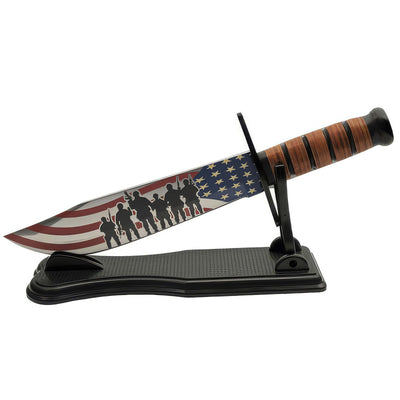 Freedom Fighter Bowie Knife featuring an American flag and soldier silhouettes on the blade, with a stacked leather handle, displayed on a black stand.