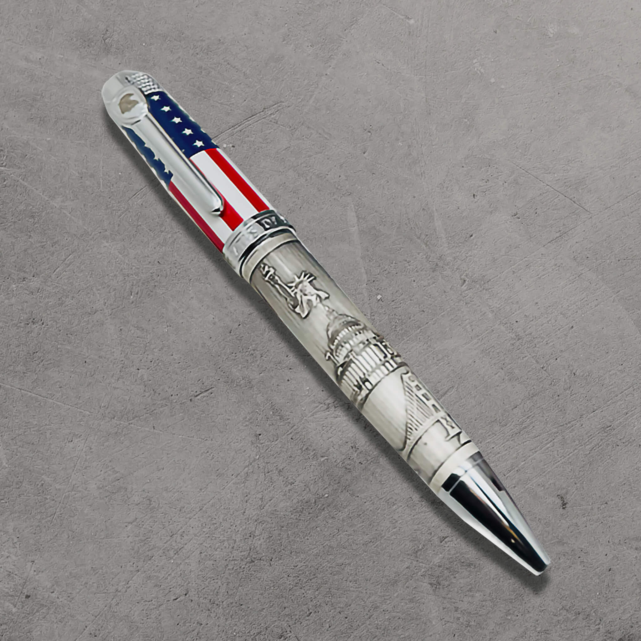 The American Journey Pen featuring a patriotic design with the U.S. flag colors and detailed engravings of iconic American landmarks on a sleek silver barrel.