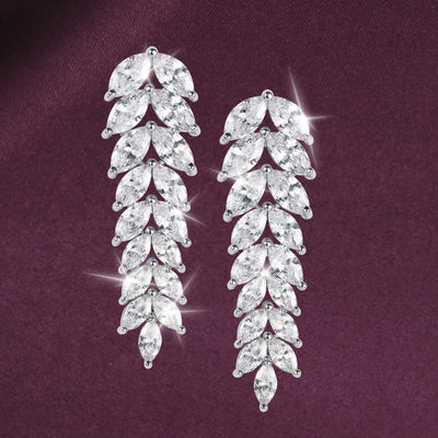Crystal Cascade Earrings featuring cascading rows of sparkling crystal leaf shapes with elegant silver toned settings on a rich burgundy background