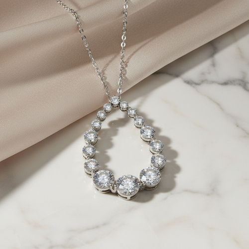 Silver necklace with a teardrop-shaped pendant on a marble surface. Daniel Steiger To Catch A Thief Pendant