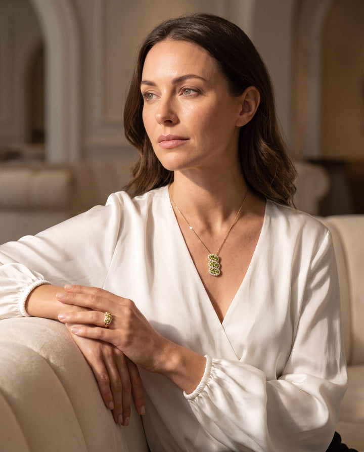 Elegant woman wearing the Elysian Peridot Pendant necklace and matching ring, showcasing vibrant green peridot gemstones in a refined setting, up to 75% off retail.
