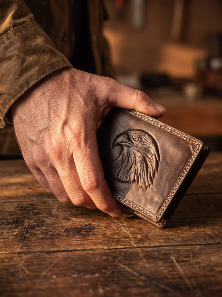 Eagle Predator Leather Wallet with embossed eagle artwork and stitched leather detailing held over a rustic wooden table Up To 75% Off Retail