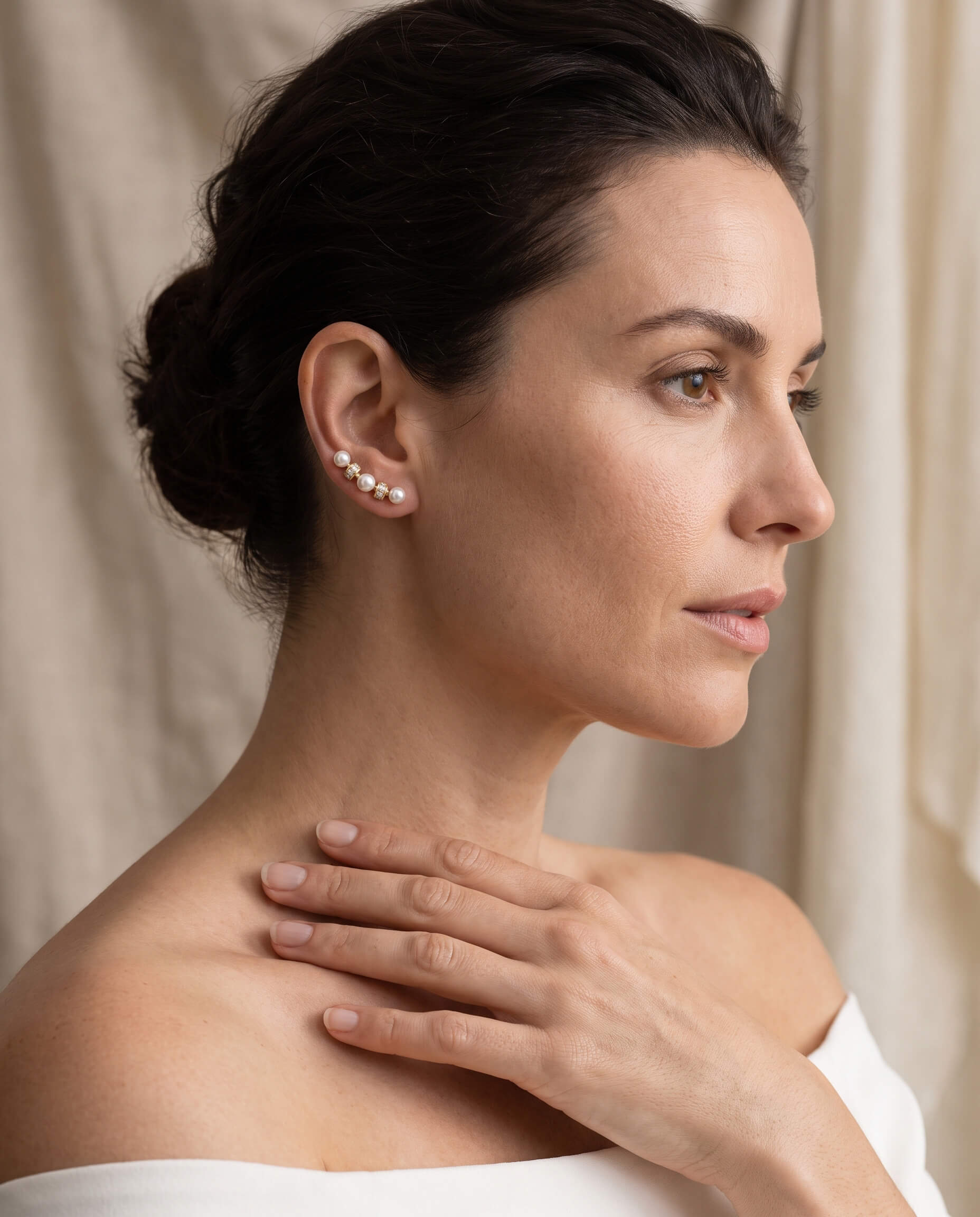 Elegant woman wearing Aria Pearl Earrings with multiple pearls ascending along the ear, showcasing sophisticated jewelry style, Up To 75% Off Retail.