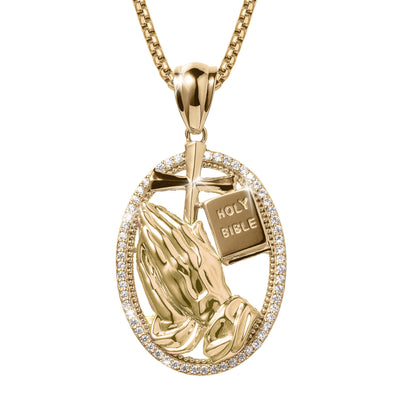 Holy Pendant featuring gold praying hands, a cross, and a small Holy Bible surrounded by a sparkling stone-studded oval frame on a gold chain necklace.
