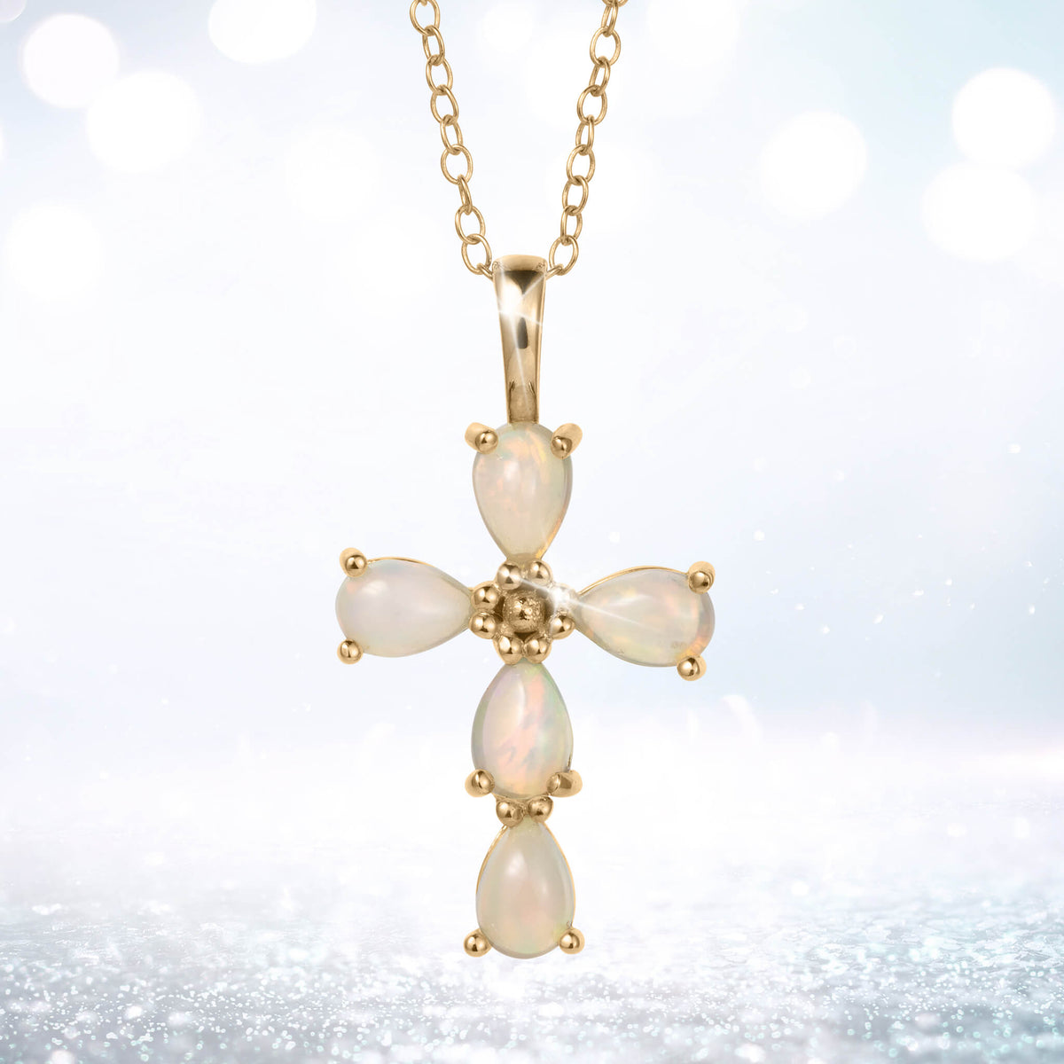 Ayana Opal Cross Pendant with luminous opal stones in a cross design on a gold tone chain against a softly glowing background