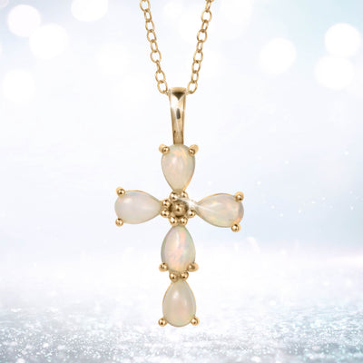 Ayana Opal Cross Pendant with luminous opal stones in a cross design on a gold tone chain against a softly glowing background
