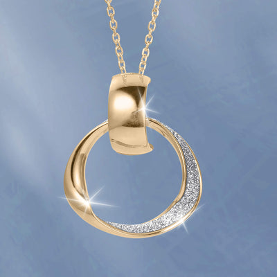 Gold circular pendant necklace with a polished curved bail and sparkling stone accents against a soft blue background