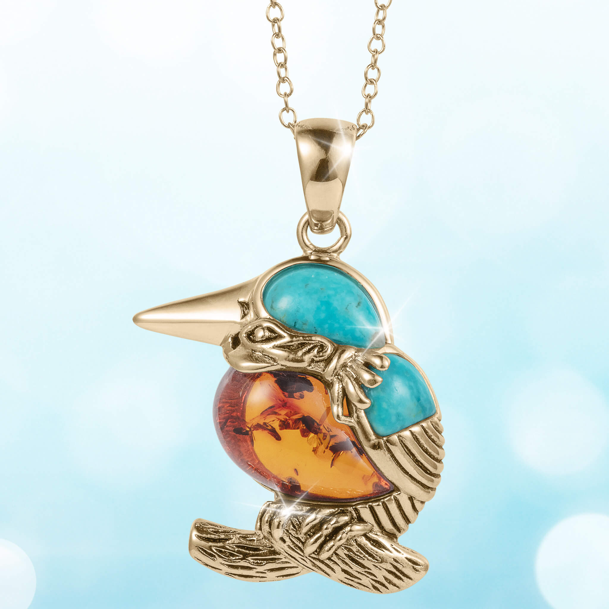 Golden Kingfisher Pendant featuring a gold-tone bird design with blue and amber-colored stone accents on a delicate chain necklace.