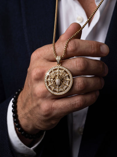 The Webmaster Pendant ornate circular gold necklace pendant with intricate web design and sparkling accents held in a hand Up To 75% Off Retail