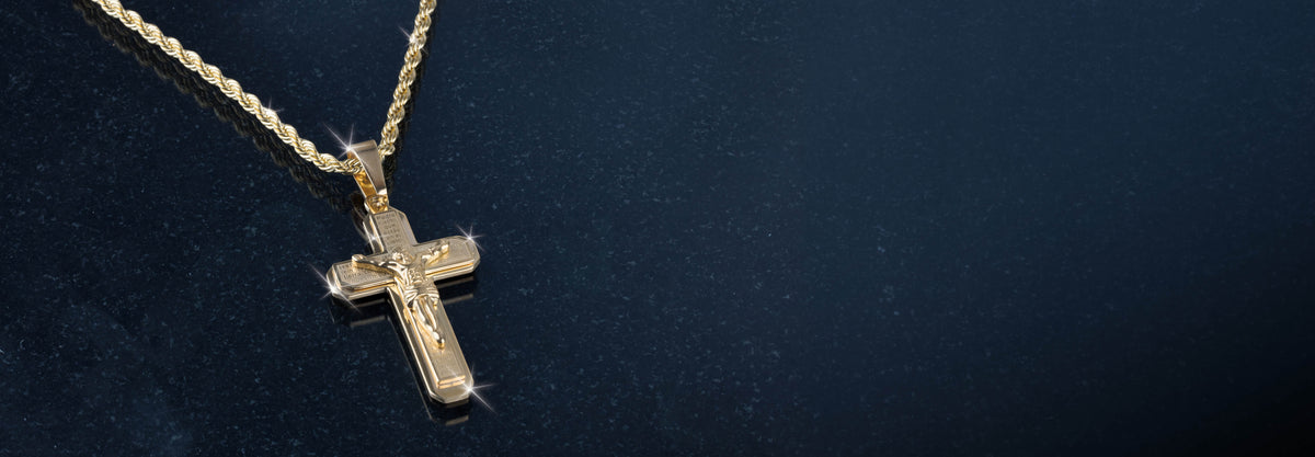 Gold cross pendant necklace resting against a dark textured background with polished surfaces catching the light