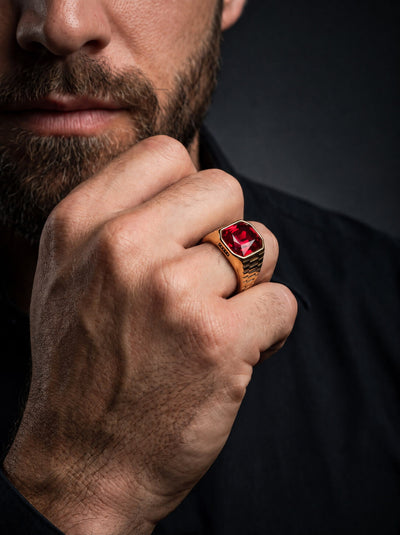 Imperial Scarlet Ring with a vivid red gemstone and ornate gold toned setting worn on a male hand in a sophisticated portrait