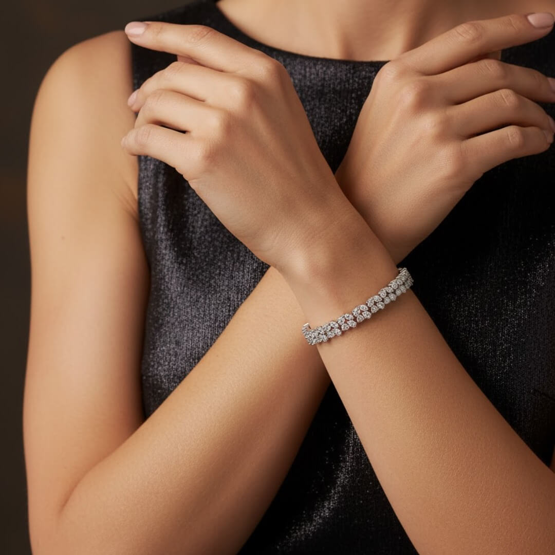 Close-up of a person wearing a silver bracelet on a dark background. Diamond bracelet on a gray surface. Versailles bracelet by Daniel Steiger.