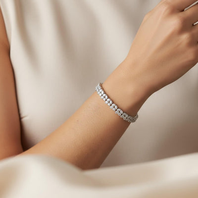 Silver bracelet on a wrist with a neutral background. Diamond bracelet on a gray surface. Versailles bracelet by Daniel Steiger.