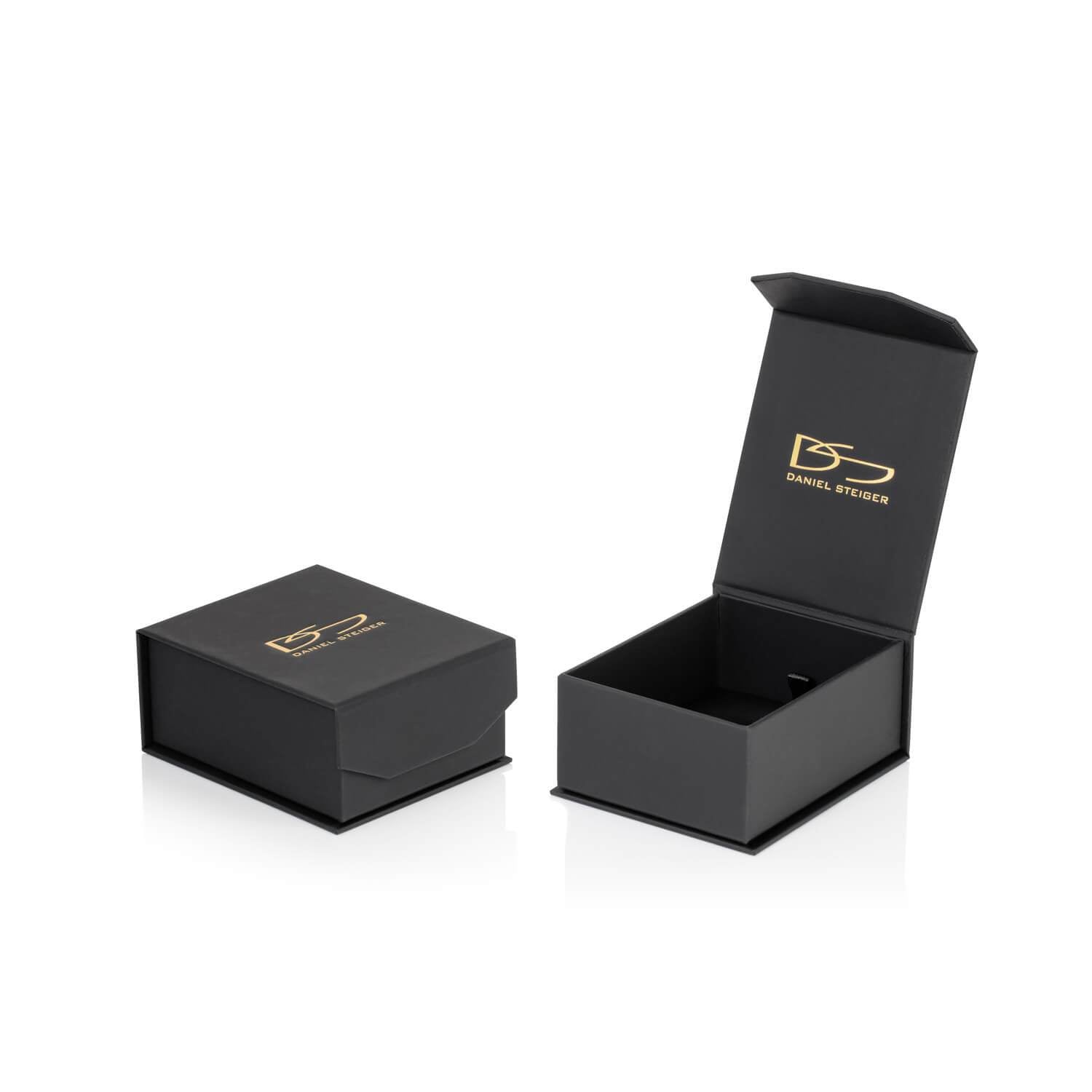 Two black jewelry boxes for the Skull Cross Rhodium Pendant, one closed and one open, featuring gold embossed branding on the lids.