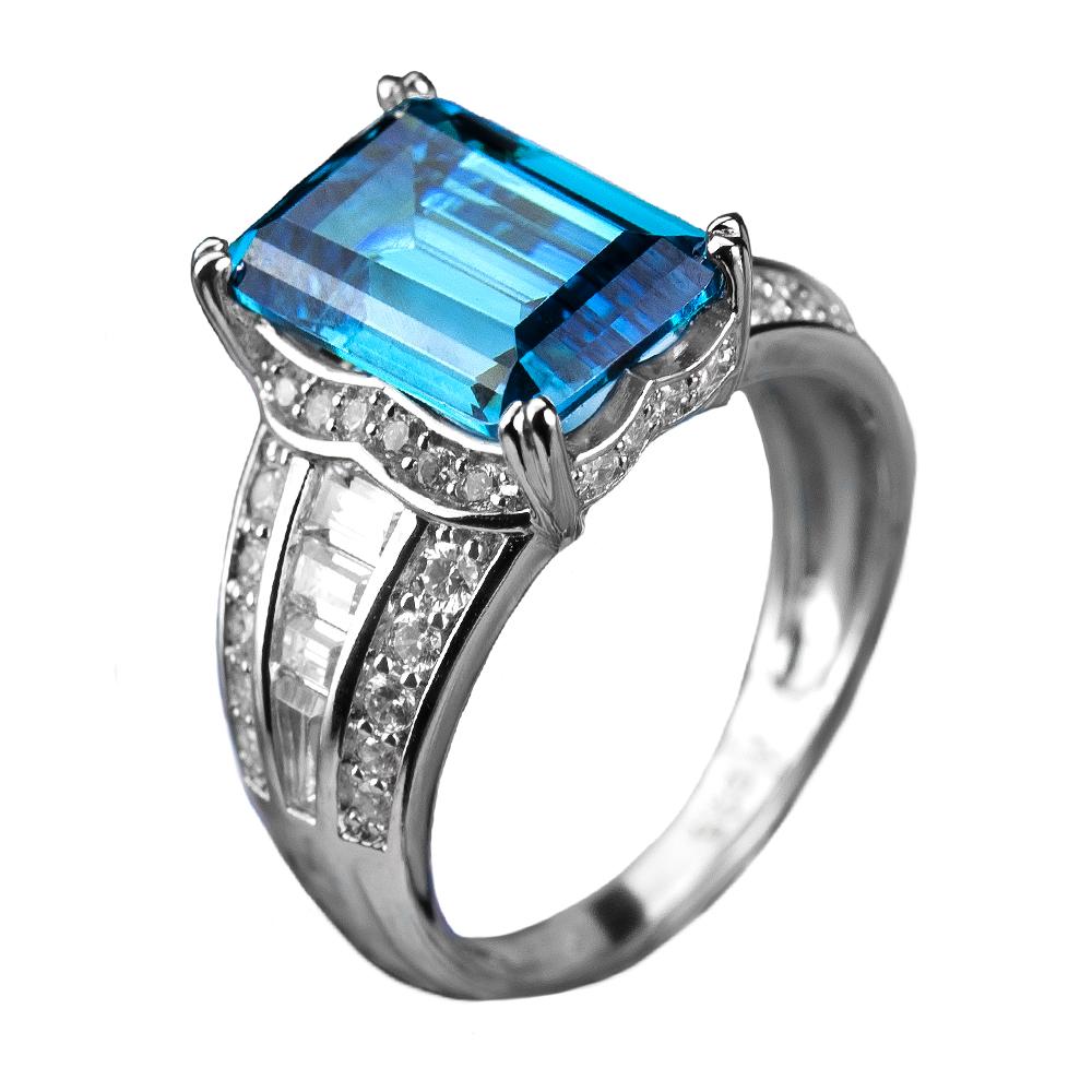 Orianna Rhodium Ring featuring a sterling silver band with rhodium plating and a large rectangular blue gemstone, accented by smaller clear stones for a luxurious jewelry piece.