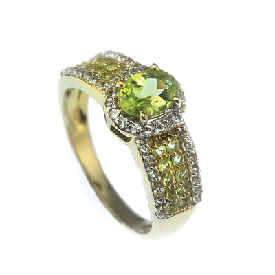 Peridot Eden Ring featuring a gold-plated sterling silver band with a central round peridot gemstone surrounded by smaller peridot and clear stones, designed for women’s jewelry.